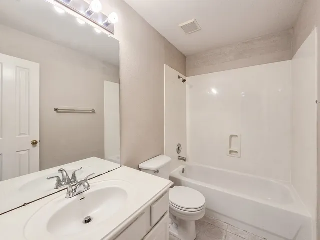 a bathroom with a bathtub shower sink mirror vanity and toilet