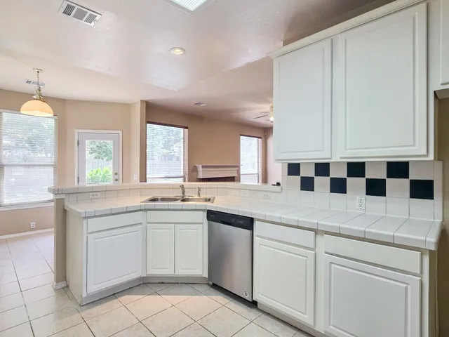 a kitchen with a sink dishwasher a stove and white cabinets