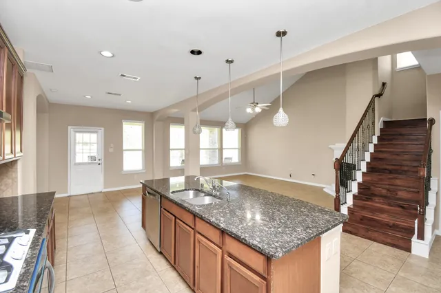 a large kitchen with kitchen island a sink stainless steel appliances and a chandelier