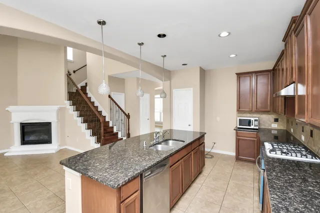 a kitchen with stainless steel appliances granite countertop a sink dishwasher stove top oven and refrigerator with wooden floor