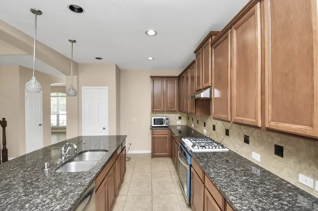 a large kitchen with kitchen island granite countertop a sink a counter space and stainless steel appliances