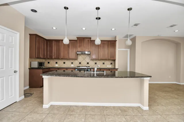 a large kitchen with stainless steel appliances kitchen island granite countertop a refrigerator a sink and a oven