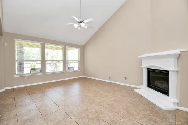 an empty room with chandelier fan and windows