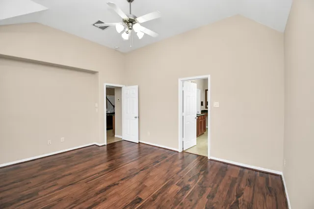 an empty room with wooden floor and ceiling fan