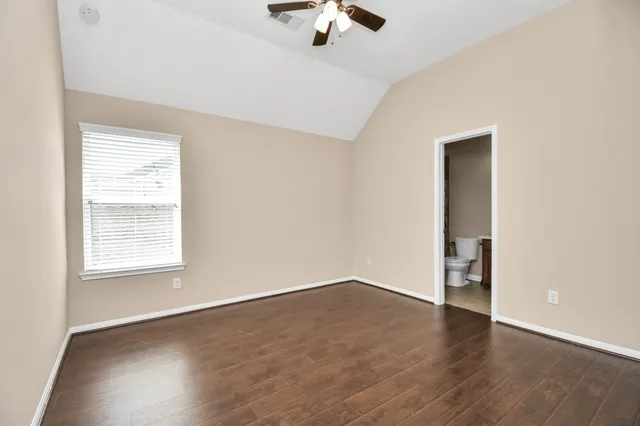 an empty room with wooden floor chandelier fan and windows