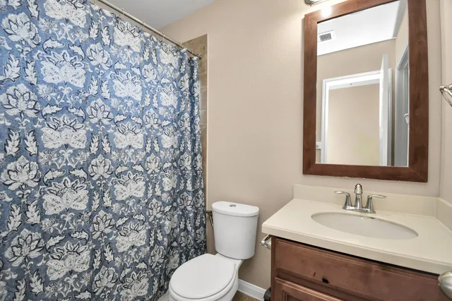 a bathroom with a granite countertop sink and a toilet