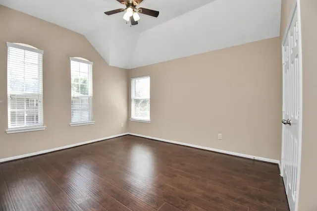 a view of an empty room with a window and wooden floor