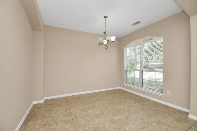 an empty room with chandelier fan and windows