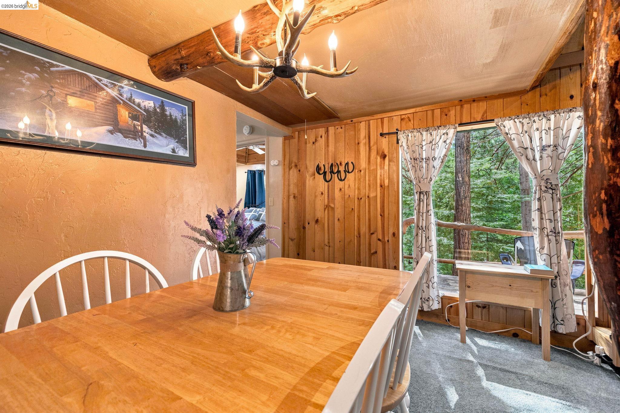 26457 Crystal Road Long Barn, CA 95335 - Photo 16 of 39 Dining area featuring a wood-finish dining table, a rustic antler-style chandelier, and a wood-paneled wall