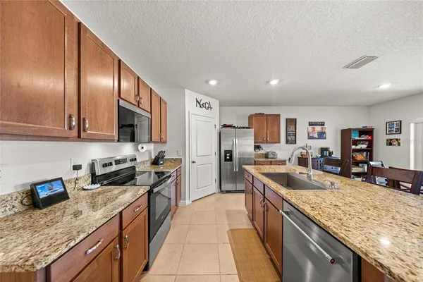 a kitchen with stainless steel appliances granite countertop sink stove refrigerator and cabinets