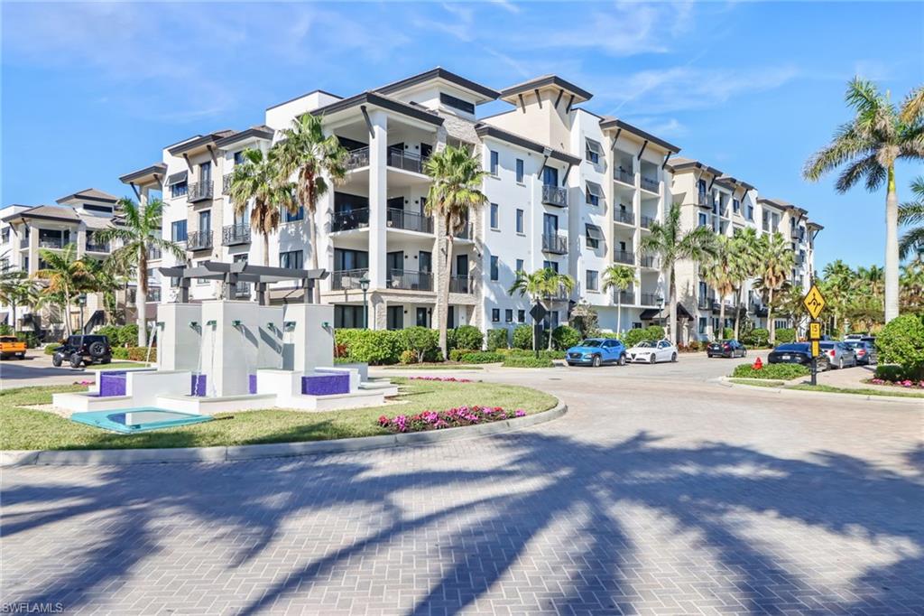 1135 3rd Avenue South, Unit 415 Naples, FL 34102 - Photo 19 of 25 a front view of multi story residential apartment building with yard and traffic signal