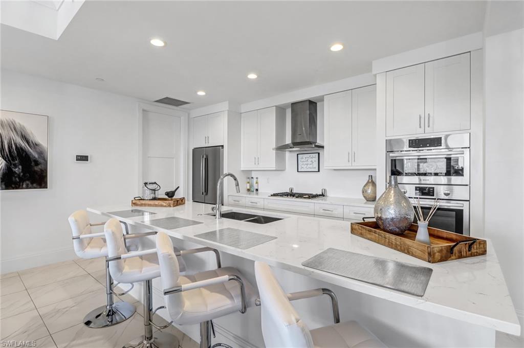 1135 3rd Avenue South, Unit 415 Naples, FL 34102 - Photo 22 of 25 a kitchen with stainless steel appliances kitchen island granite countertop a sink and cabinets