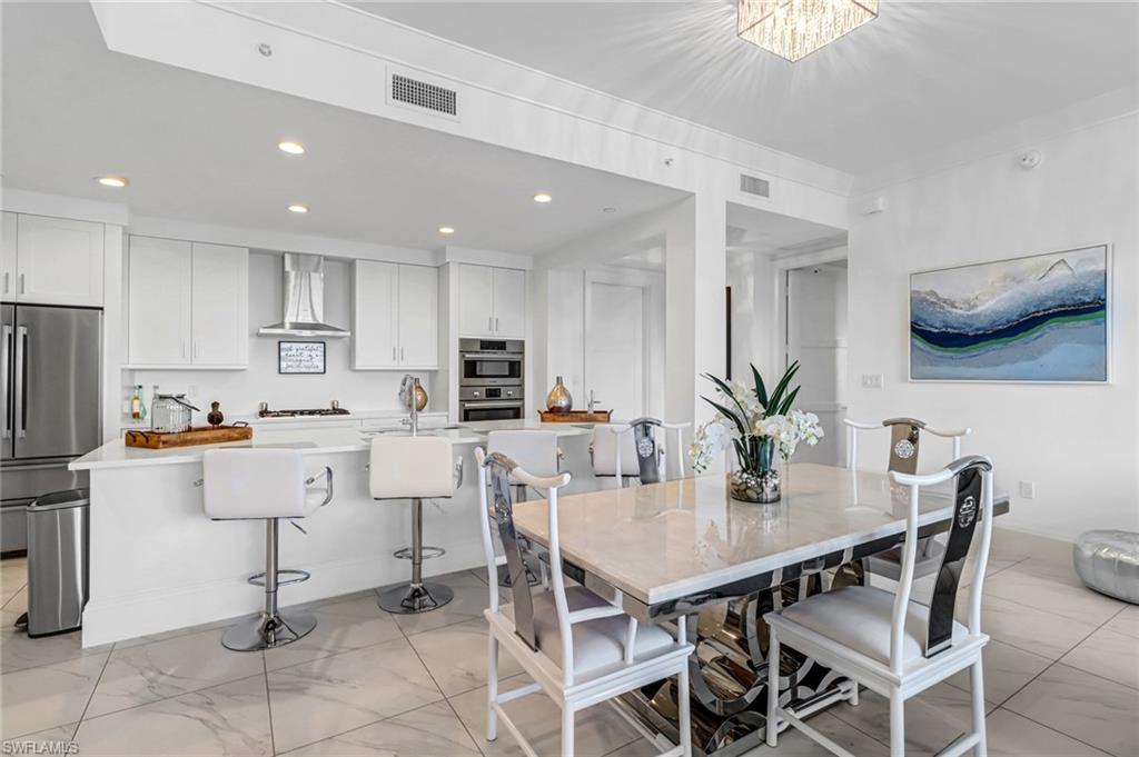 1135 3rd Avenue South, Unit 415 Naples, FL 34102 - Photo 2 of 25 a kitchen with stainless steel appliances kitchen island granite countertop a dining table chairs and a refrigerator