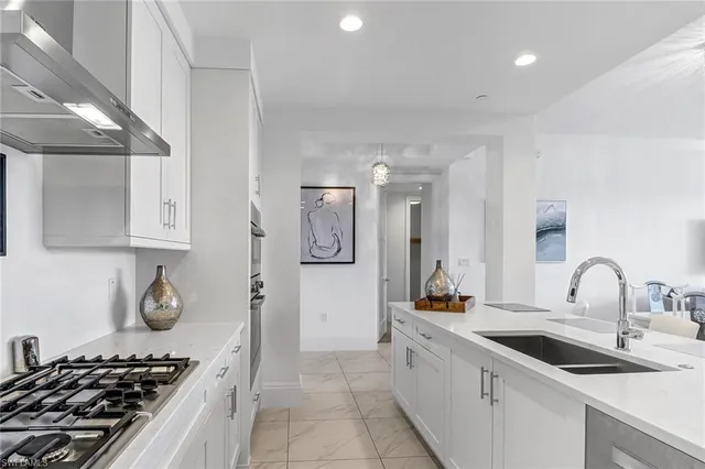 a kitchen with stainless steel appliances kitchen island granite countertop a dining table chairs and a refrigerator