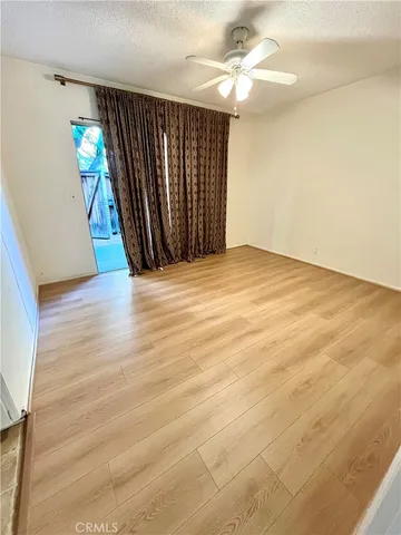 an empty room with wooden floor staircase and hallway
