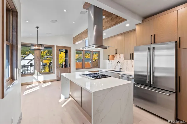 a kitchen with stainless steel appliances granite countertop a refrigerator a sink dishwasher a stove and a dining table with wooden floor