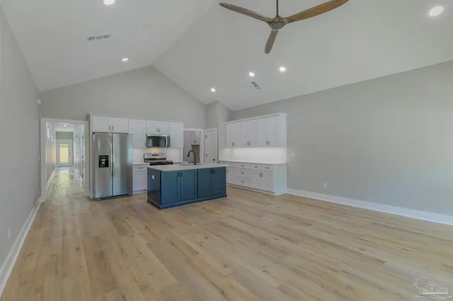 a large white kitchen with a sink and dishwasher a oven with wooden floor