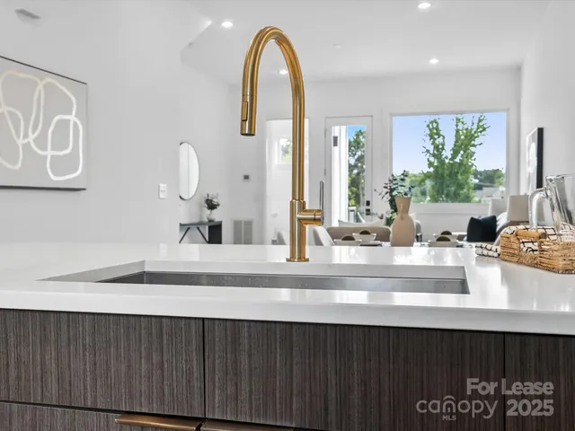a closeup of a sink with a large mirror next to a window