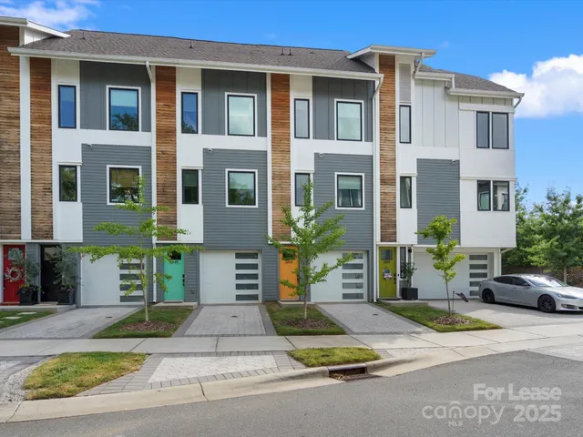 a view of a brick house with potted plants and a large tree