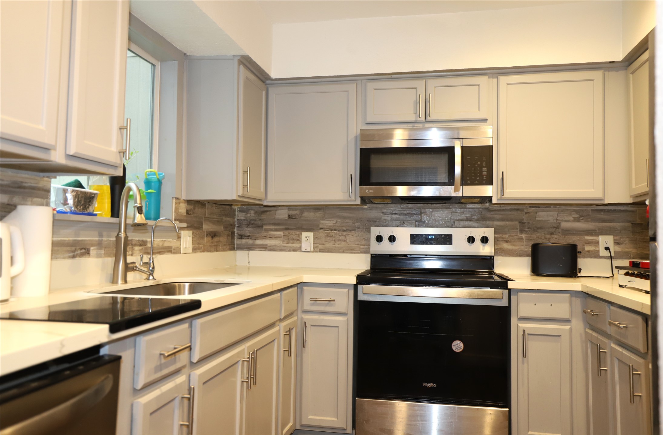2103 Place Rebecca Lane, Unit D6 Houston, TX 77090 - Photo 8 of 31 a kitchen with stainless steel appliances granite countertop a sink a stove a microwave a counter space and cabinets