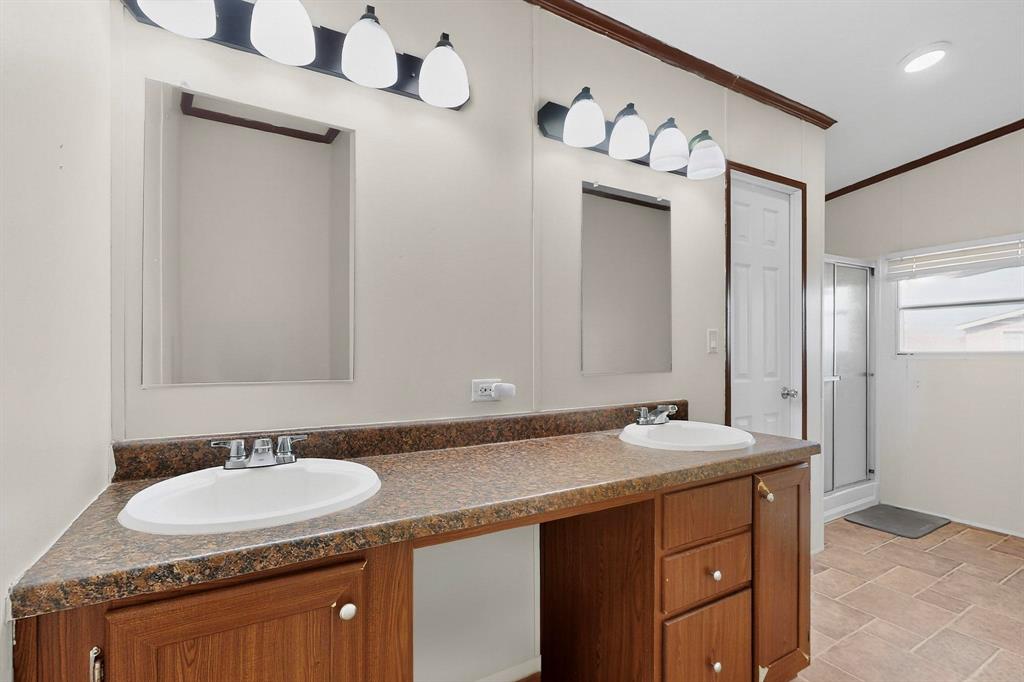 1406 Grand Prix Court Rhome, TX 76078 - Photo 4 of 12 Bathroom featuring a shower stall, double vanity, ornamental molding, and stone finish flooring