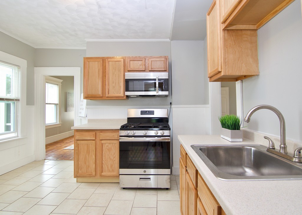 a kitchen with granite countertop a stove a sink and a microwave