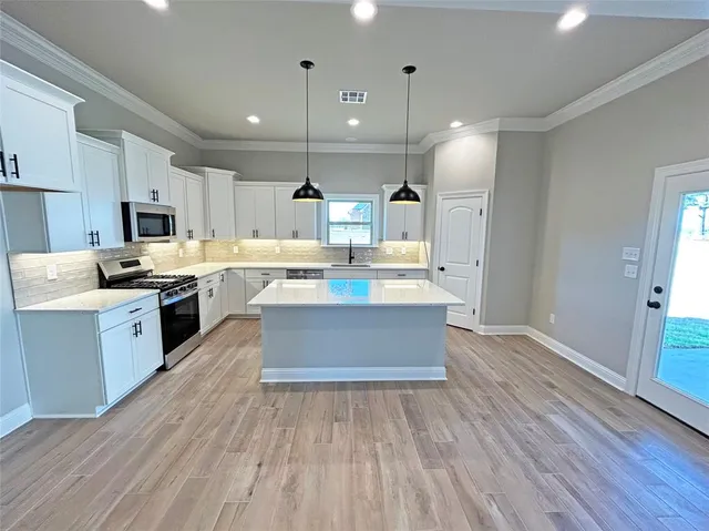 a large kitchen with a center island and wooden floor