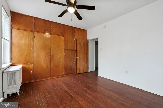 an empty room with wooden floor closet and windows