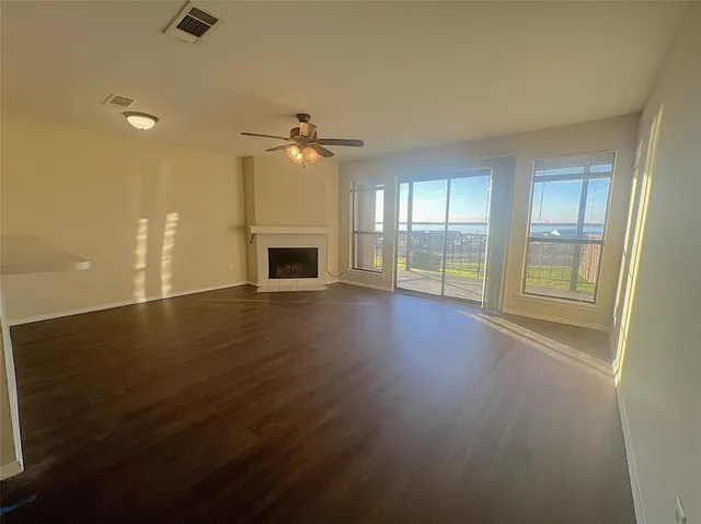 an empty room with wooden floor fireplace and windows