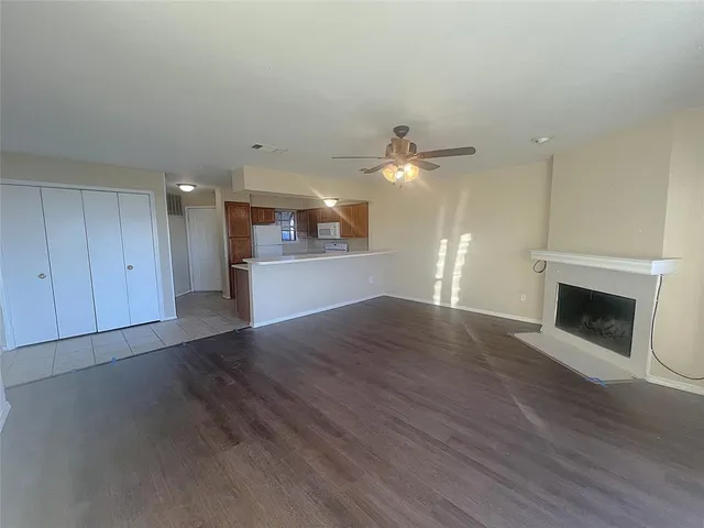 an empty room with wooden floor fireplace and windows