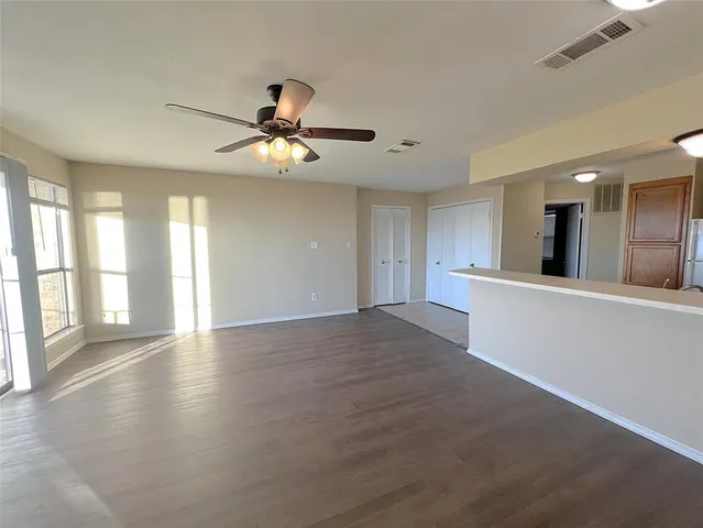 a view of an empty room with window and a kitchen view