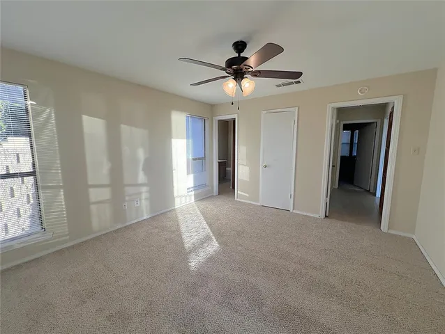 a view of a big room with windows and chandelier fan
