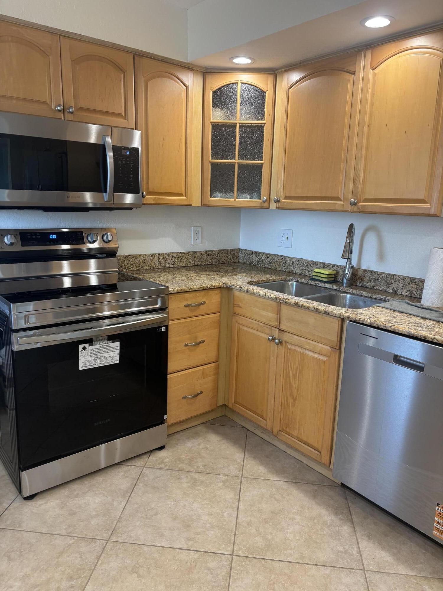 6461 Northwest 2nd Avenue, Unit 313 Boca Raton, FL 33487 - Photo 2 of 9 a kitchen with stainless steel appliances granite countertop a stove microwave and cabinets