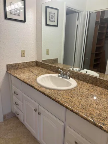 a bathroom with a granite countertop sink and a mirror
