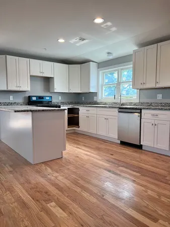 a kitchen with granite countertop a stove top oven sink and cabinets