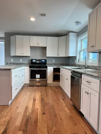 a kitchen with granite countertop a stove top oven sink and cabinets