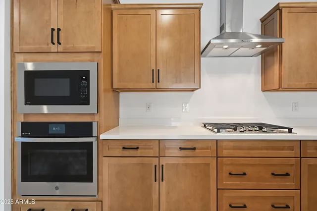 a kitchen with stainless steel appliances granite countertop a stove top oven a sink a counter space and cabinets