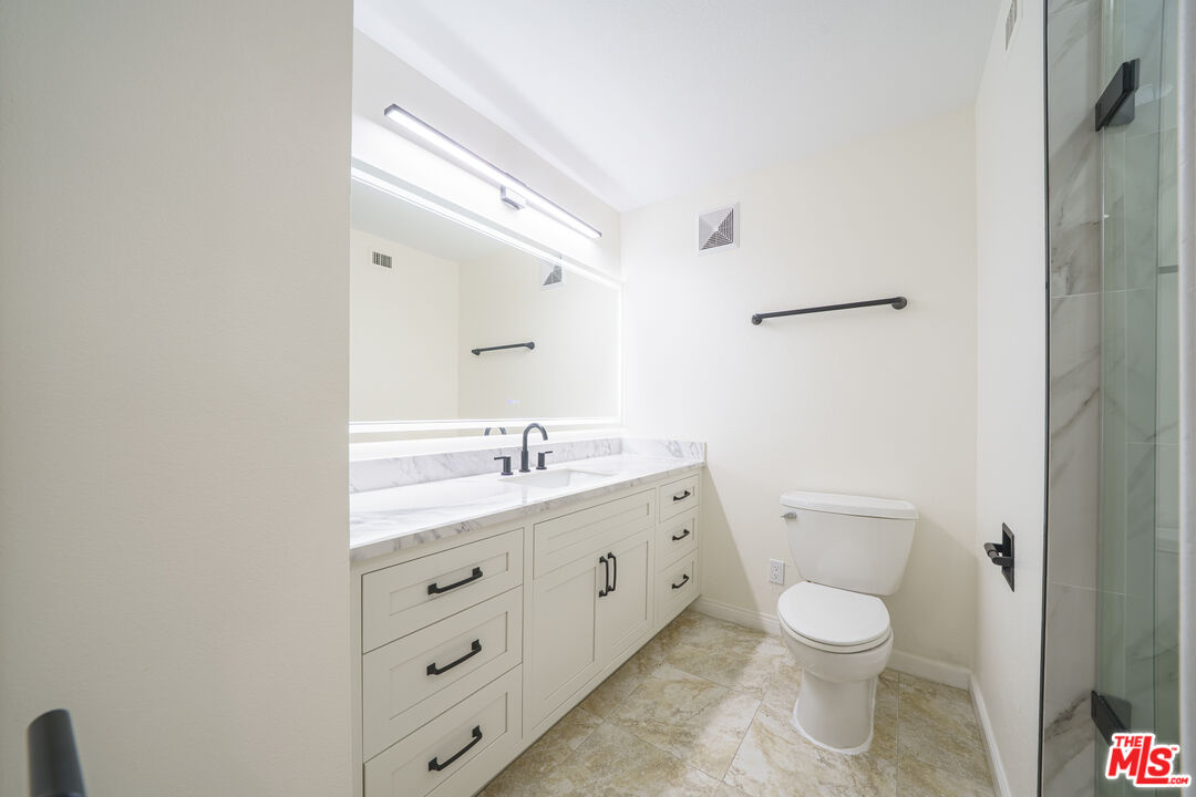 600 West 9th Street, Unit 1502 Los Angeles, CA 90015 - Photo 22 of 37 a bathroom with a granite countertop toilet sink and mirror