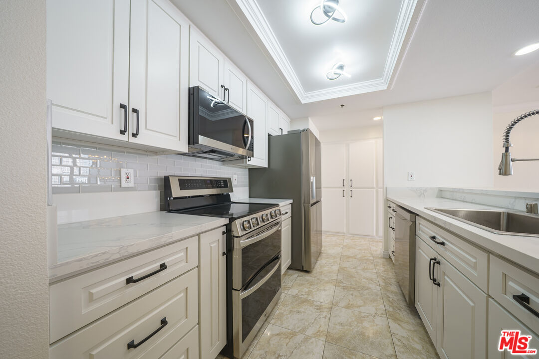 600 West 9th Street, Unit 1502 Los Angeles, CA 90015 - Photo 5 of 37 a kitchen with stainless steel appliances granite countertop a stove top oven a sink dishwasher and a refrigerator with wooden cabinets