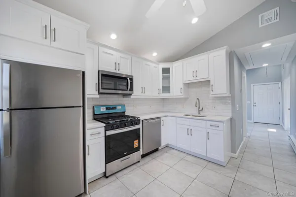 a kitchen with white cabinets stainless steel appliances and a counter space