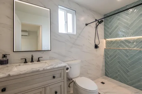 a bathroom with a granite countertop sink mirror vanity and toilet