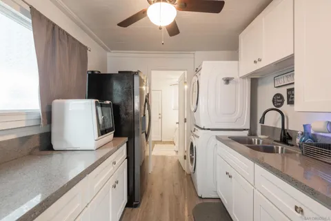 a kitchen with stainless steel appliances a refrigerator a sink a stove and white cabinets with wooden floor