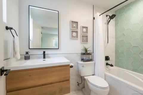 a bathroom with a granite countertop sink toilet a mirror a vanity and shower