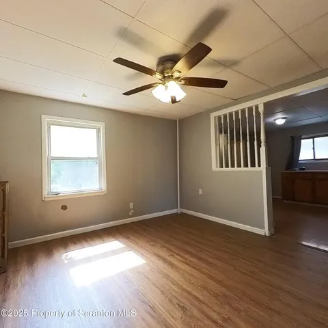 a view of an empty room with a window and wooden floor