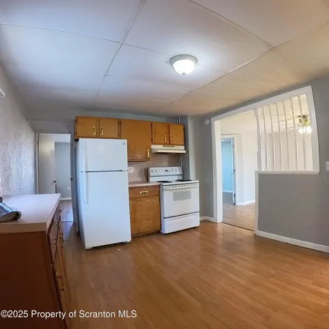 a kitchen with a refrigerator a stove top oven a counter space and wooden floor