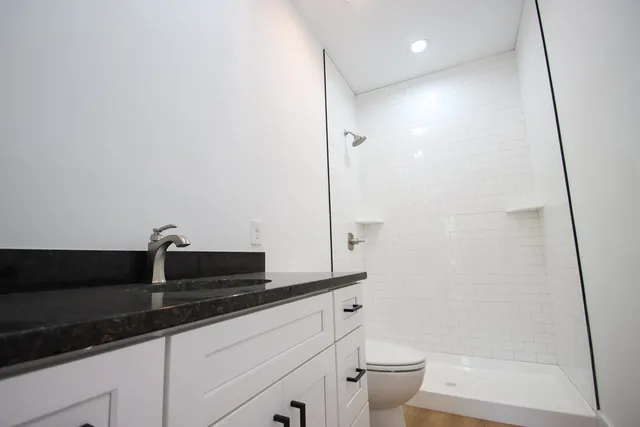 a bathroom with a granite countertop sink a toilet and shower