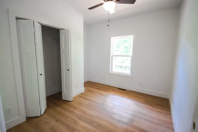 an empty room with wooden floor cabinet and windows