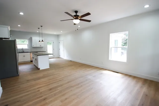 a kitchen with stainless steel appliances granite countertop a refrigerator a sink dishwasher a stove and white countertops with wooden floor