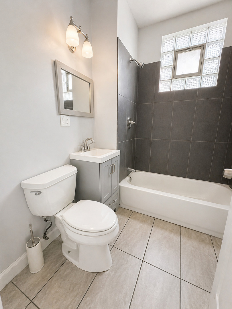 2114 West 51st Street, Unit 1 Chicago, IL 60609 - Photo 7 of 9 a bathroom with a toilet a sink a window and mirror