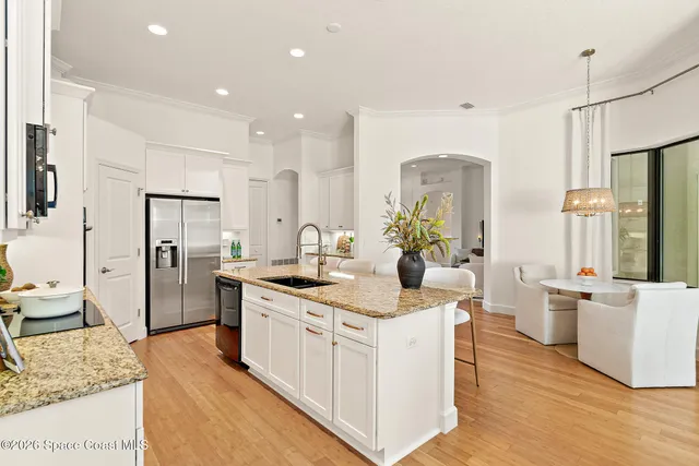 a kitchen with stainless steel appliances granite countertop a refrigerator a stove top oven a sink dishwasher and white cabinets with wooden floor